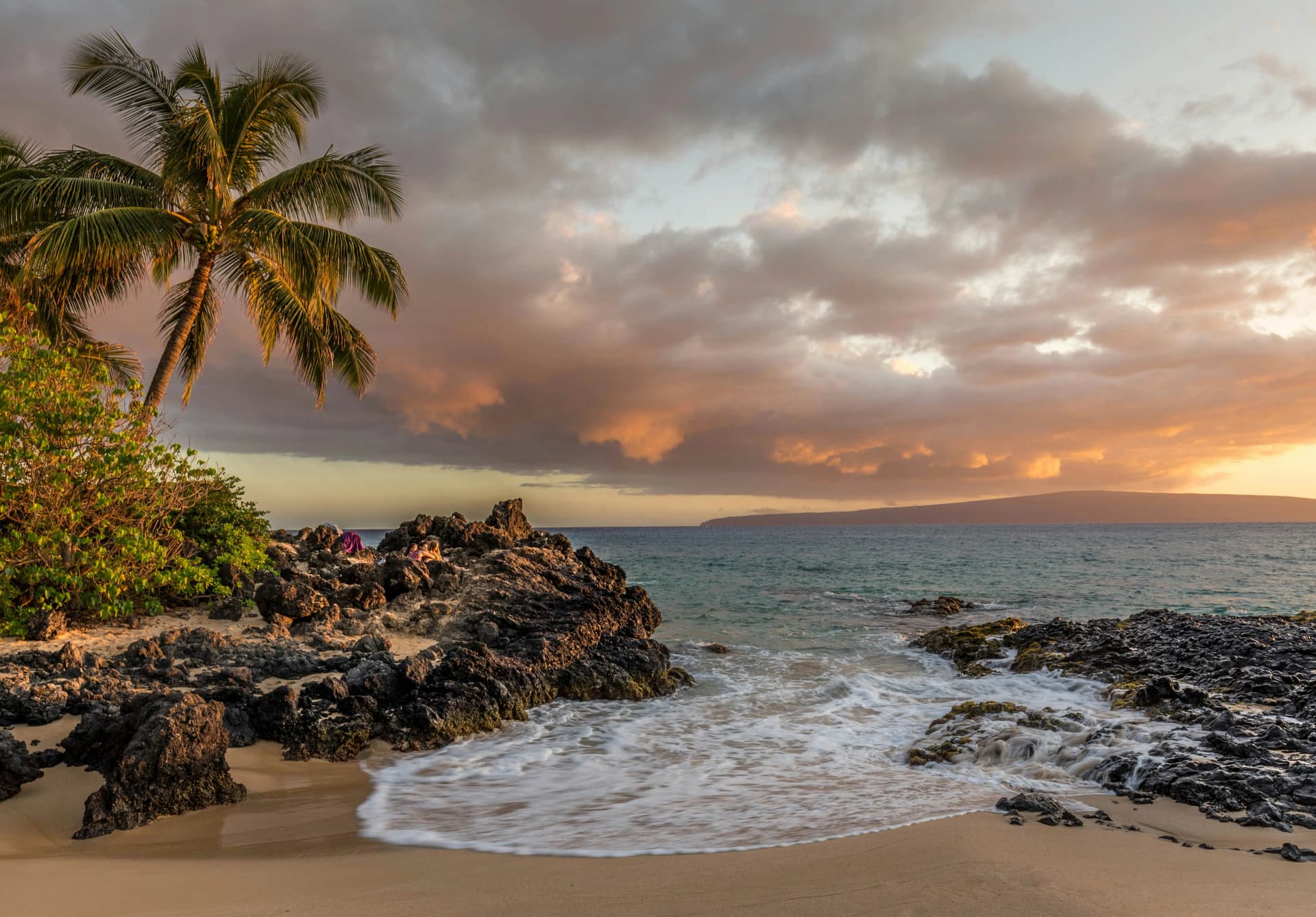 A beautiful beach scene in Hawaii with turquoise water and volcanic rock.