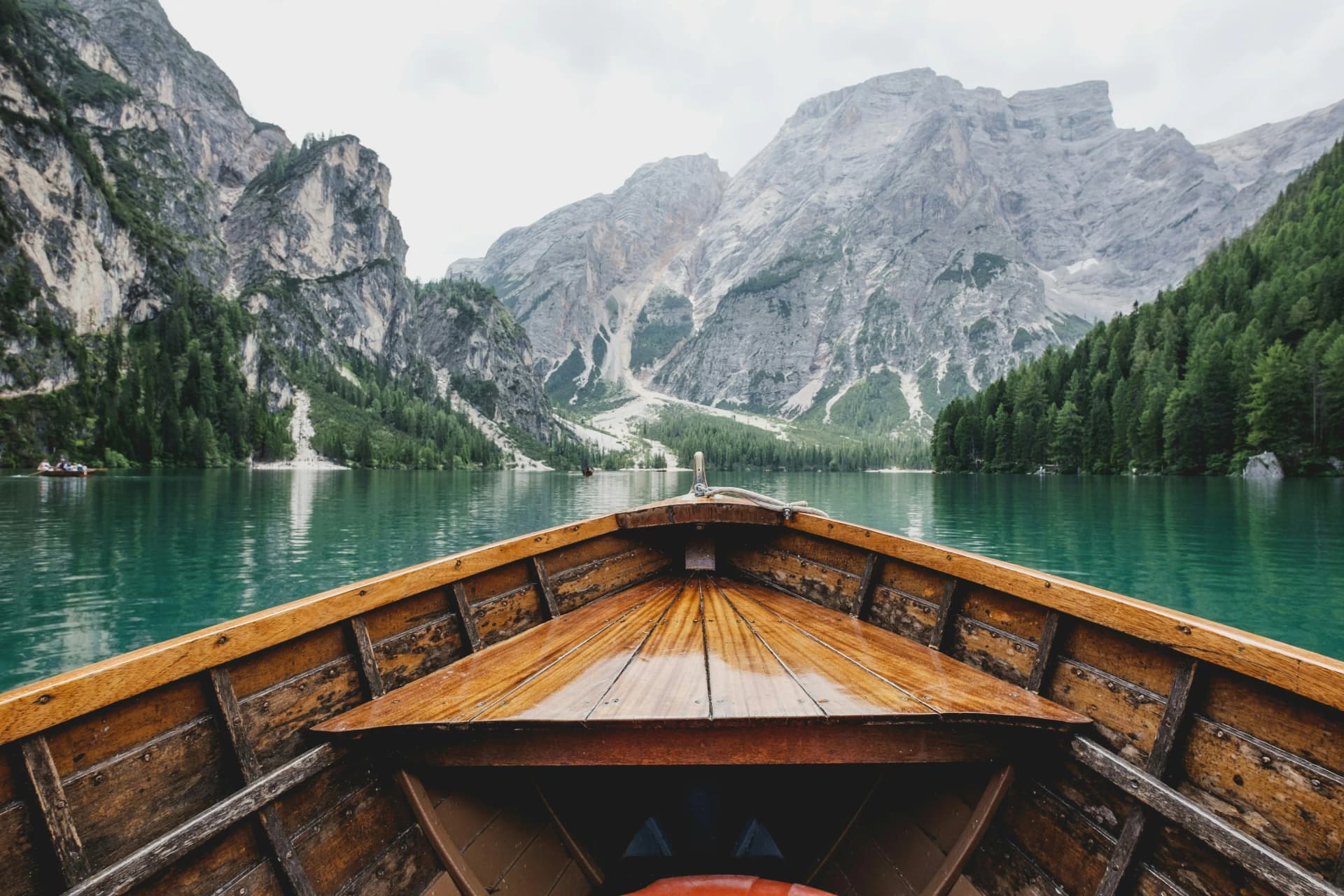 Wooden rowboat on a tranquil turquoise lake surrounded by majestic mountains, illustrating a travel reward destination.