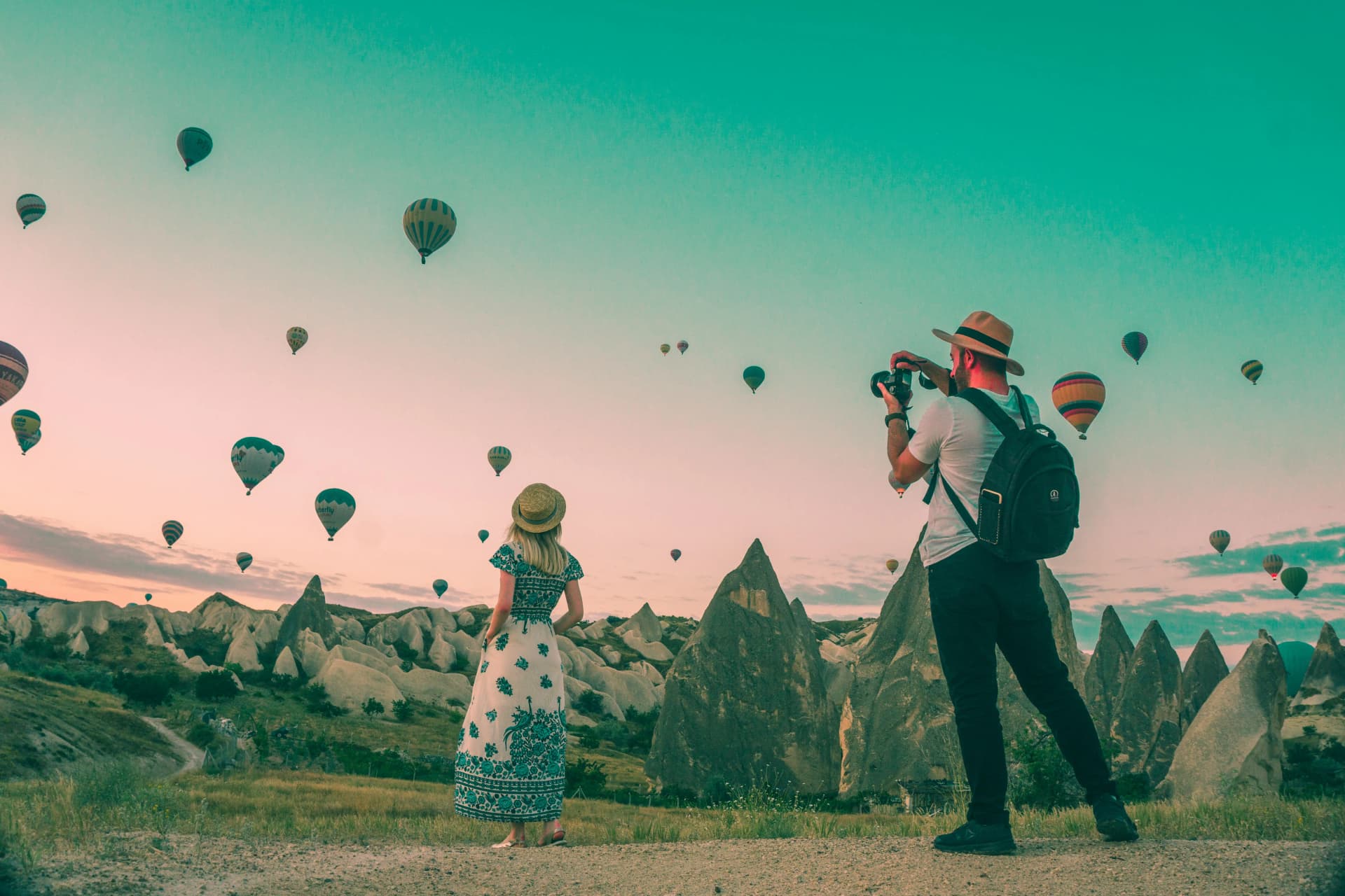 Travelers looking at hot air balloons over a scenic landscape, symbolizing experiences unlocked by travel rewards.