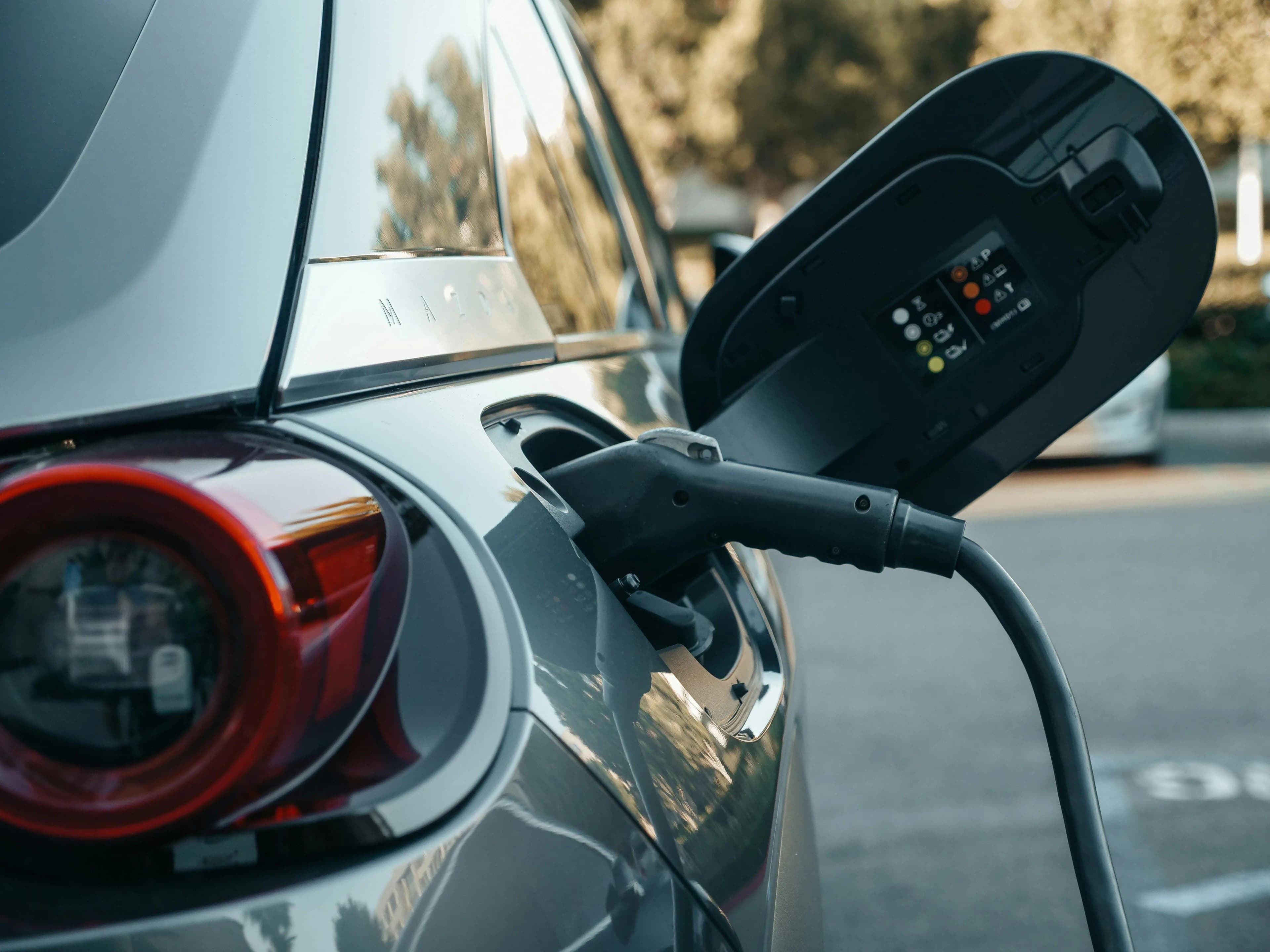 An electric car plugged into a charging station with a scenic mountain landscape in the background.